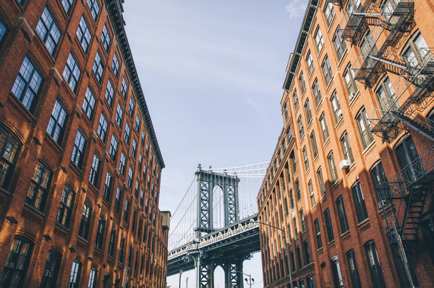 Manhattan bridge seen from a red brick buildings in Brooklyn street in perspective, New York, USA - Фото, зображення