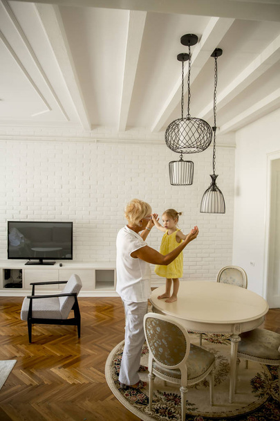 Grandmother and cute granddaughter having fun in the room - Photo, Image