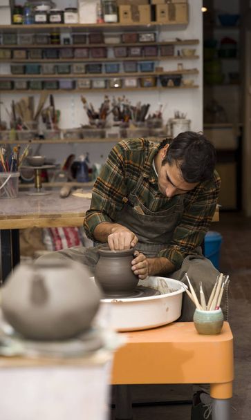 Вид на художника, делающего глиняную посуду на вращающемся колесе
 - Фото, изображение