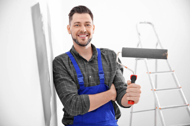 Young male decorator painting wall in room - Photo, image
