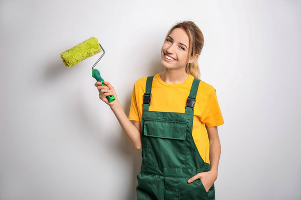 Young female decorator with paint roller on white background - Fotografie, Obrázek