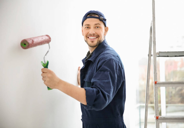 Young male decorator painting wall in room - Foto, Imagem