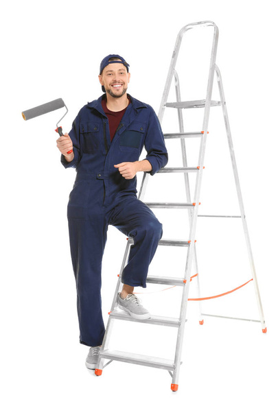 Young male decorator with paint roller on white background - Foto, afbeelding