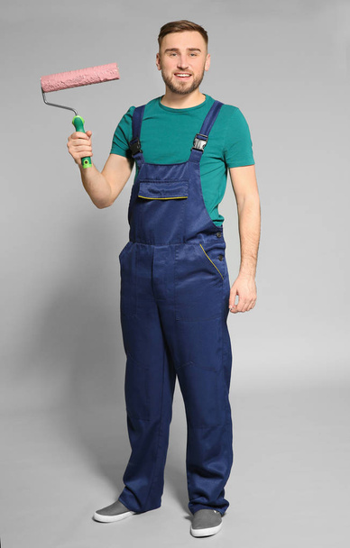 Young male decorator with paint roller on color background - Valokuva, kuva