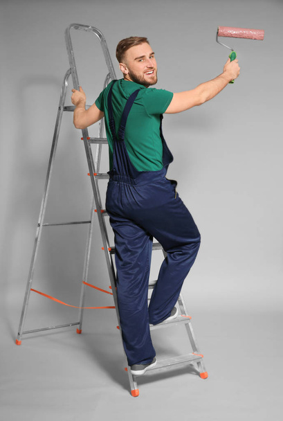 Young male decorator with paint roller on color background - Foto, Imagem