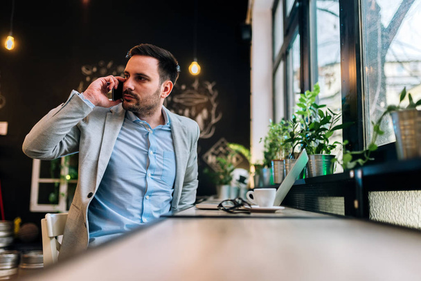 Entrepreneur talking on phone about meeting with partner in cafe. - Photo, Image