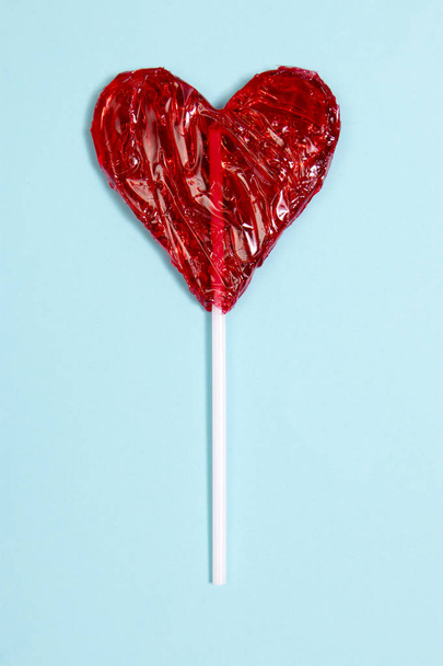 the red Lollipop candy in heart shape on dark blue background. - Fotografie, Obrázek