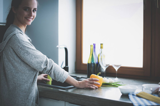 Beautiful young woman washing vegetables for salad while standing in the kitchen - Valokuva, kuva
