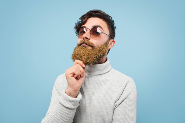 Thoughtful man in sunglasses touching beard - Foto, Imagen