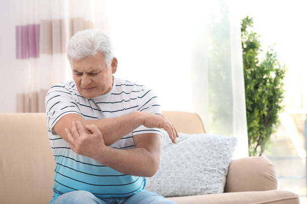 Mature man suffering from elbow pain at home - Foto, immagini