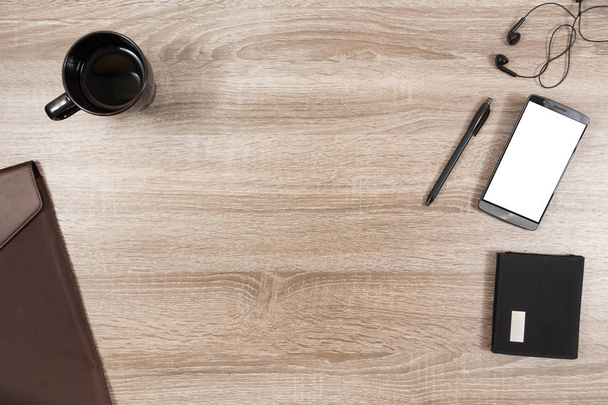 wooden desk with smartphone, headphones, pen, wallet, coffee mug - Foto, afbeelding