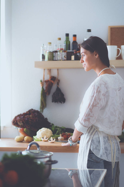 Young woman standing near desk in the kitchen - Foto, imagen