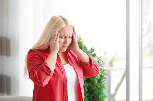 Mujer madura que sufre de dolor de cabeza en casa - Foto, Imagen