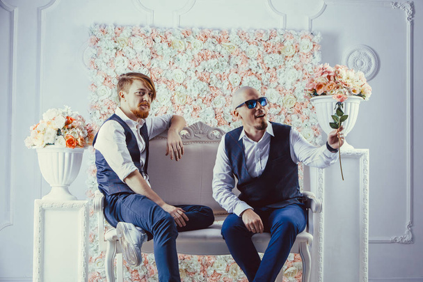 Two hipsters are sitting on the sofa and waiting for their girlfriends - Фото, изображение