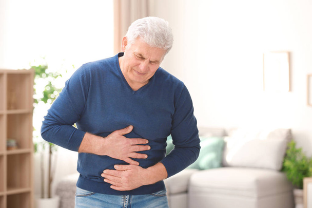 Mature man suffering from stomach ache at home - Foto, immagini