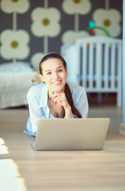 Young beautiful woman at home sitting on the floor with laptop - Photo, image