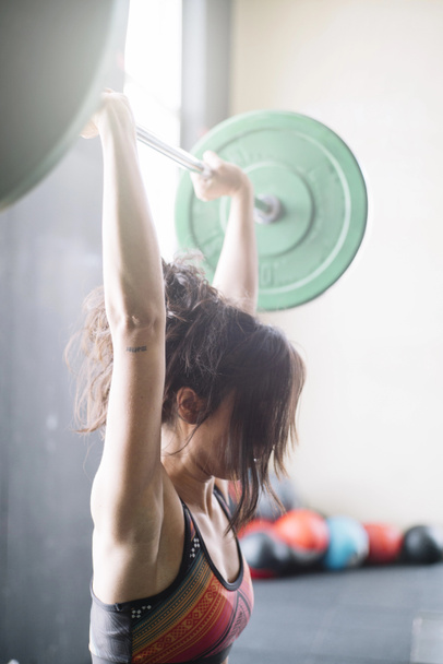 Determined sportswoman lifting heavy barbell - Photo, Image