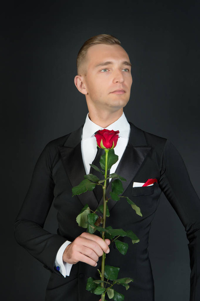 Man in suit with rose on dark background - Fotó, kép