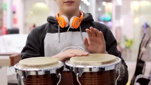 człowiek odgrywa instrumenty perkusyjne w sklepie muzycznym - Materiał filmowy, wideo