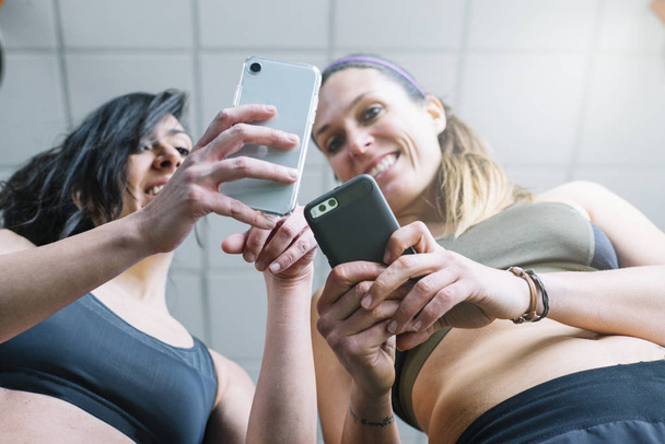 dos mujeres con teléfono en el gimnasio
 - Foto, imagen