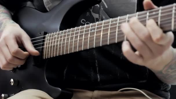 ein Mann mit Tätowierungen an den Händen, der in einem Musikladen eine E-Gitarre spielt. - Filmmaterial, Video