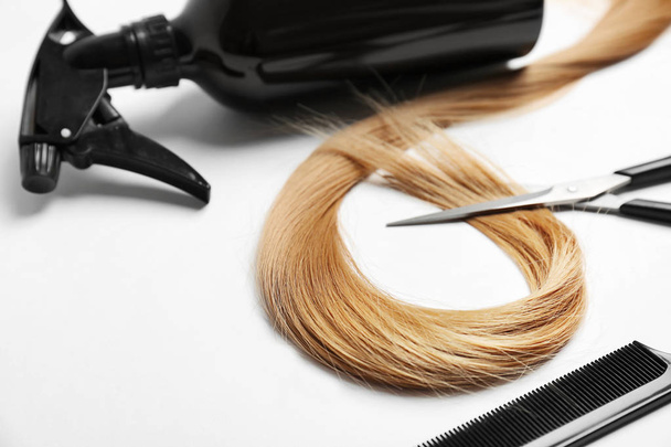 Professional hairdresser's set and strand of blonde hair on white background - Foto, afbeelding