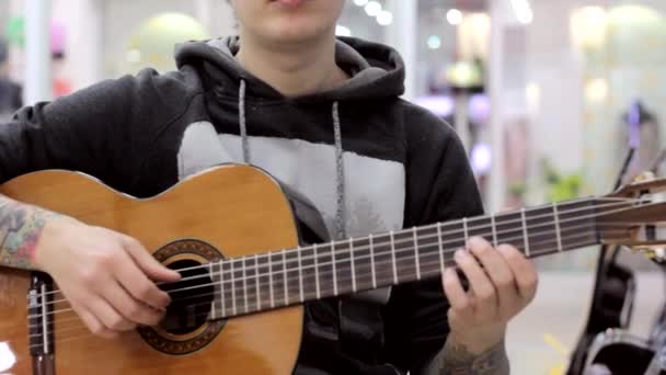 O cara toca guitarra clássica em uma loja de música, um clima musical, música clássica
. - Filmagem, Vídeo
