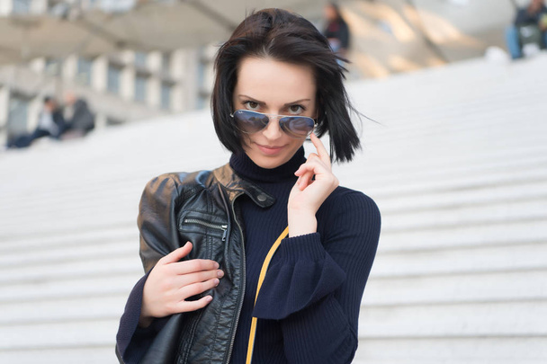 Sensual woman in sunglasses on stairs in paris, france, beauty. Woman with brunette hair in black clothes, fashion. Ambition, challenge, success. Fashion, accessory, style. Beauty, look, hairstyle - Photo, Image