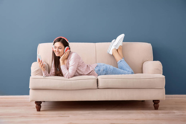 Beautiful young woman listening to music on sofa, indoors - Фото, зображення