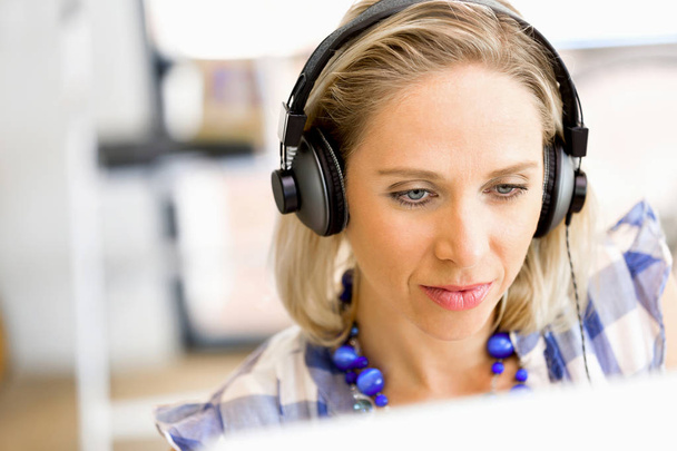 Young woman in the office with headphones - 写真・画像