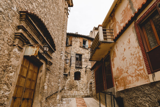 bottom view of narrow street with ancient buildings at old town, Peille, France - 写真・画像