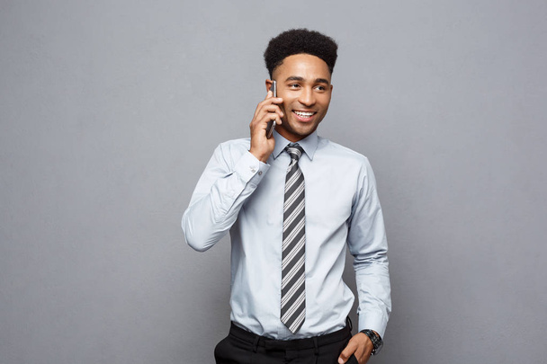 Бизнес-концепция - веселый профессиональный африканский бизнесмен счастлив разговаривать с клиентом по мобильному телефону
. - Фото, изображение