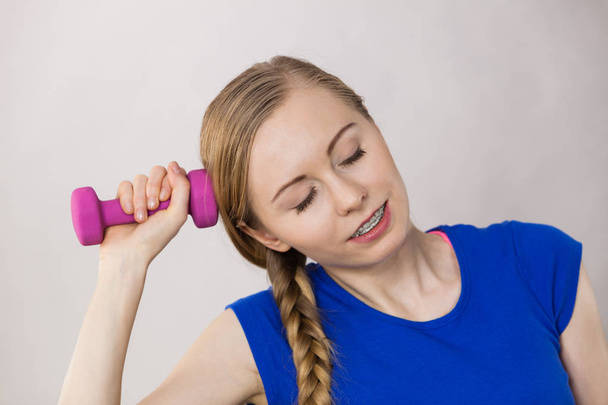 Teenage woman working out at home with dumbbell - Foto, imagen