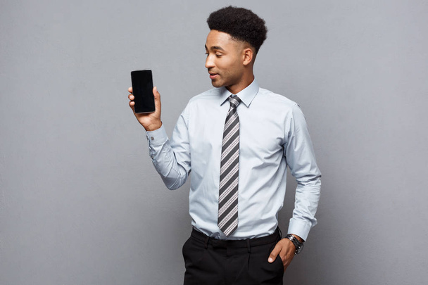 事業コンセプト - 携帯電話をクライアントに示す幸せのハンサムなプロ アフリカ系アメリカ人のビジネスマン. - 写真・画像