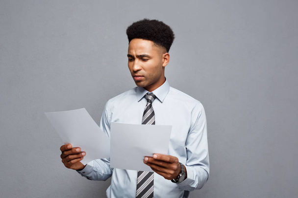 Conceito de negócio - belo jovem profissional afro-americano empresário leitura concentrada em papel de documento
. - Foto, Imagem