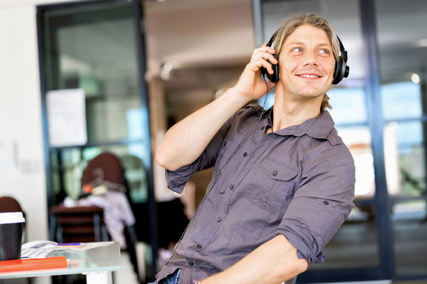 Young man in the office with headphones - Foto, Bild