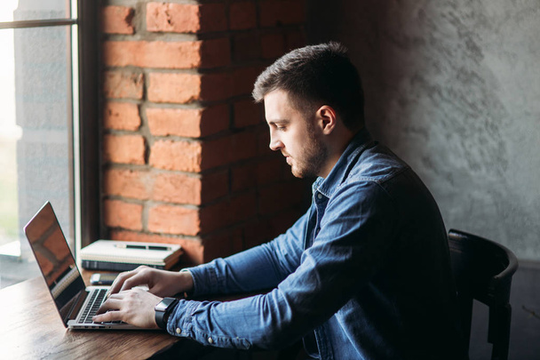 Man with a beard uses a laptop in a cafe - Zdjęcie, obraz