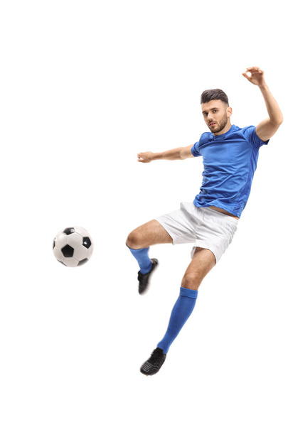 Male soccer player kicking a football in mid-air isolated on white background - Fotoğraf, Görsel