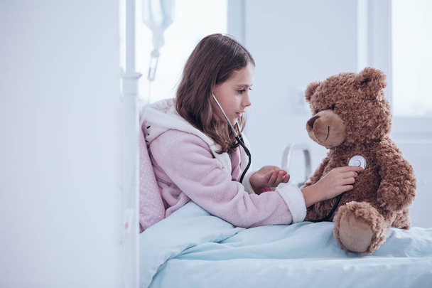 Girl examining teddy bear - Foto, immagini