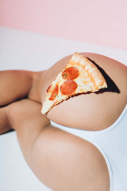 partial view of piece of pizza on female booty - Foto, Imagen