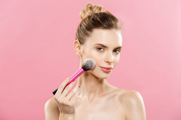 Beauty Concept - Closeup Beautiful caucasian woman applying makeup with Cosmetic Powder Brush. Perfect Skin. Isolated on pink background and copy space. - Foto, immagini