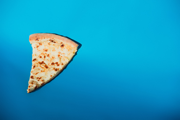 Nahaufnahme von einem Stück italienischer Pizza isoliert auf blauem Grund  - Foto, Bild