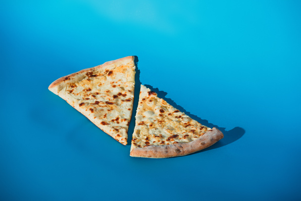 close up view of pieces of cooked pizza isolated on blue - Φωτογραφία, εικόνα
