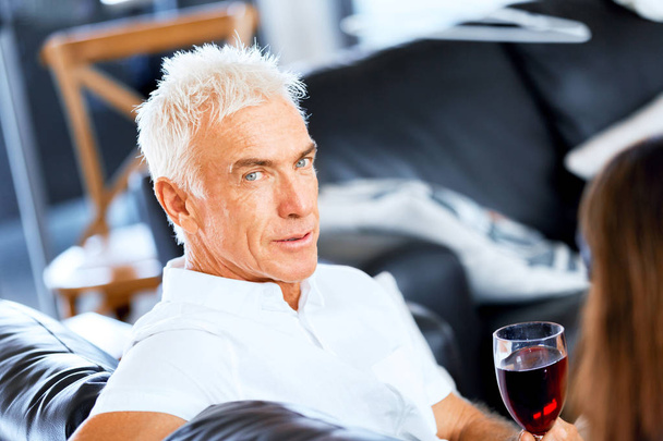 Senior man with holding a glass of wine indoors - Foto, imagen