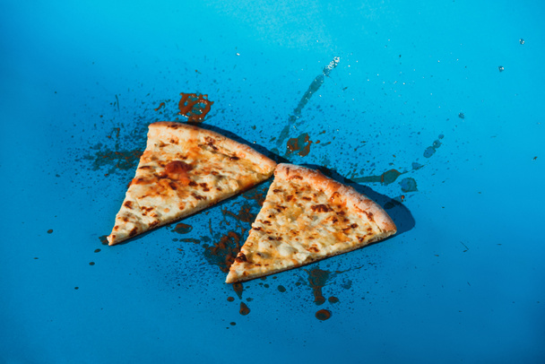 close up view of pieces of cooked pizza on blue backdrop - Photo, Image