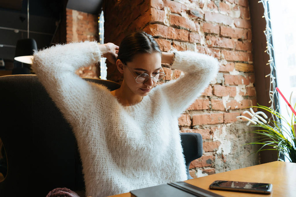 focused young girl freelancer sitting in a cafe, on a desk notepad for work - Fotografie, Obrázek
