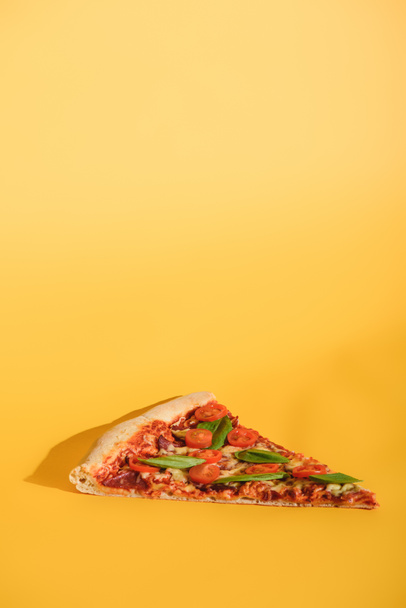 close up view of piece of pizza with cherry tomatoes and basil on orange backdrop - Фото, зображення