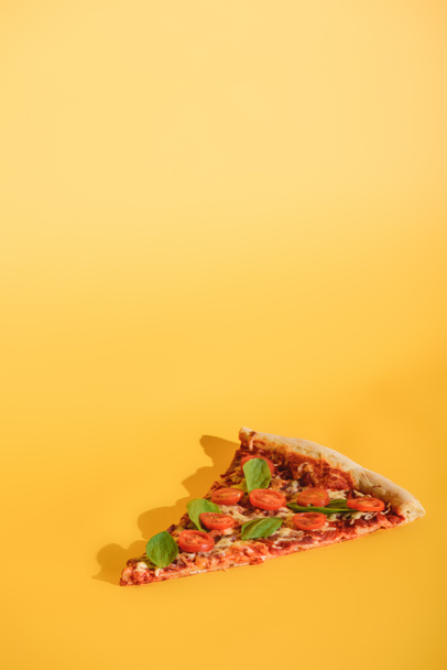 close up view of piece of pizza with cherry tomatoes and basil on orange backdrop - Fotoğraf, Görsel