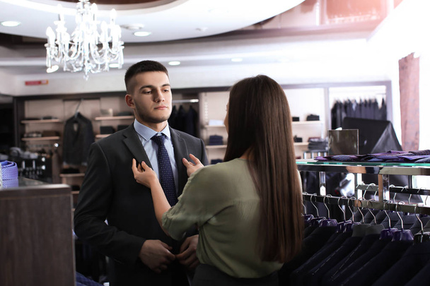 assistant helping man to choose suit - Valokuva, kuva