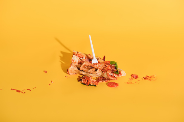 close up view of disposable fork in smashed piece of pizza on orange backdrop - Foto, imagen